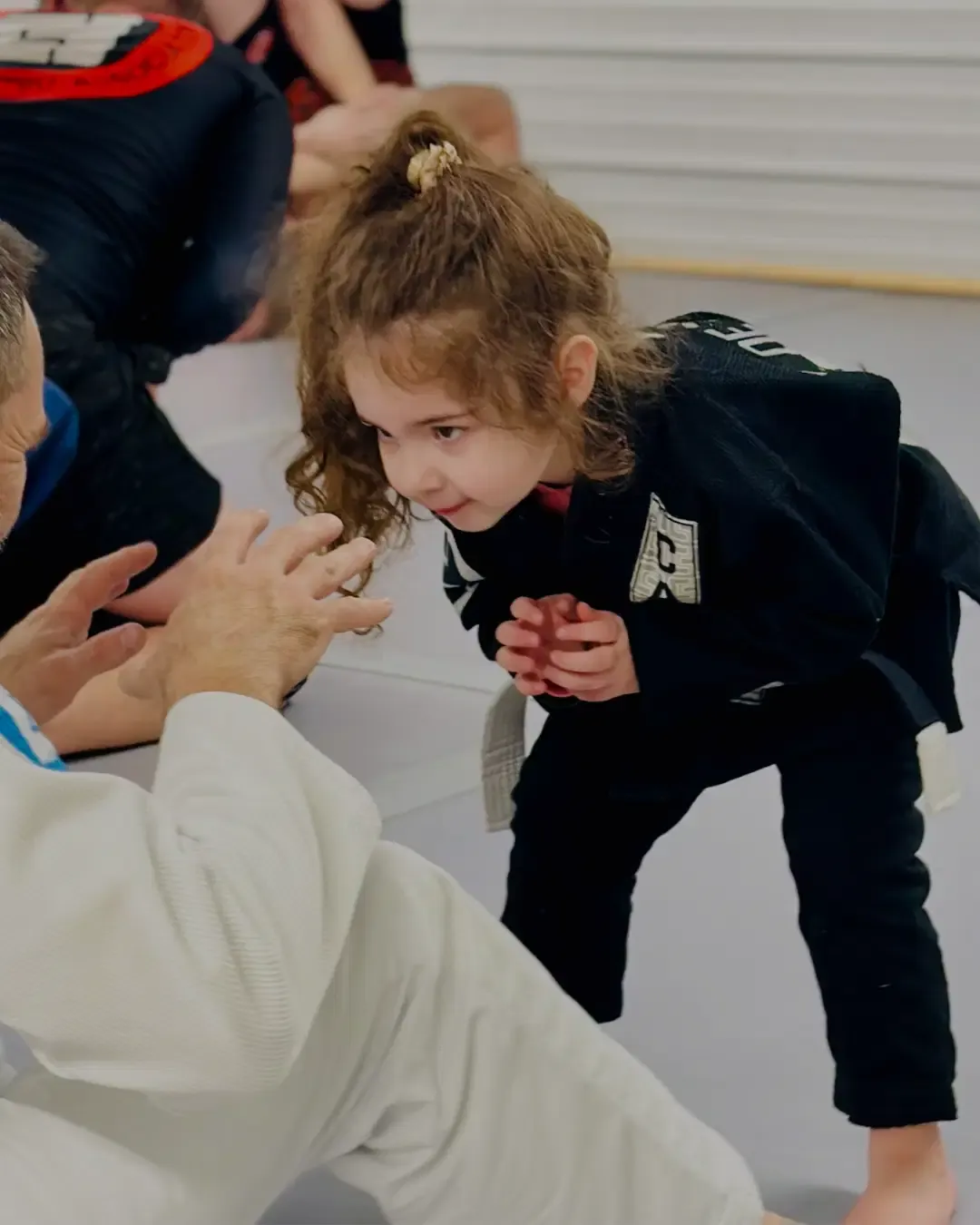 A young student in a black gi practising on the mats during a kids class at Moxie Jiu Jitsu